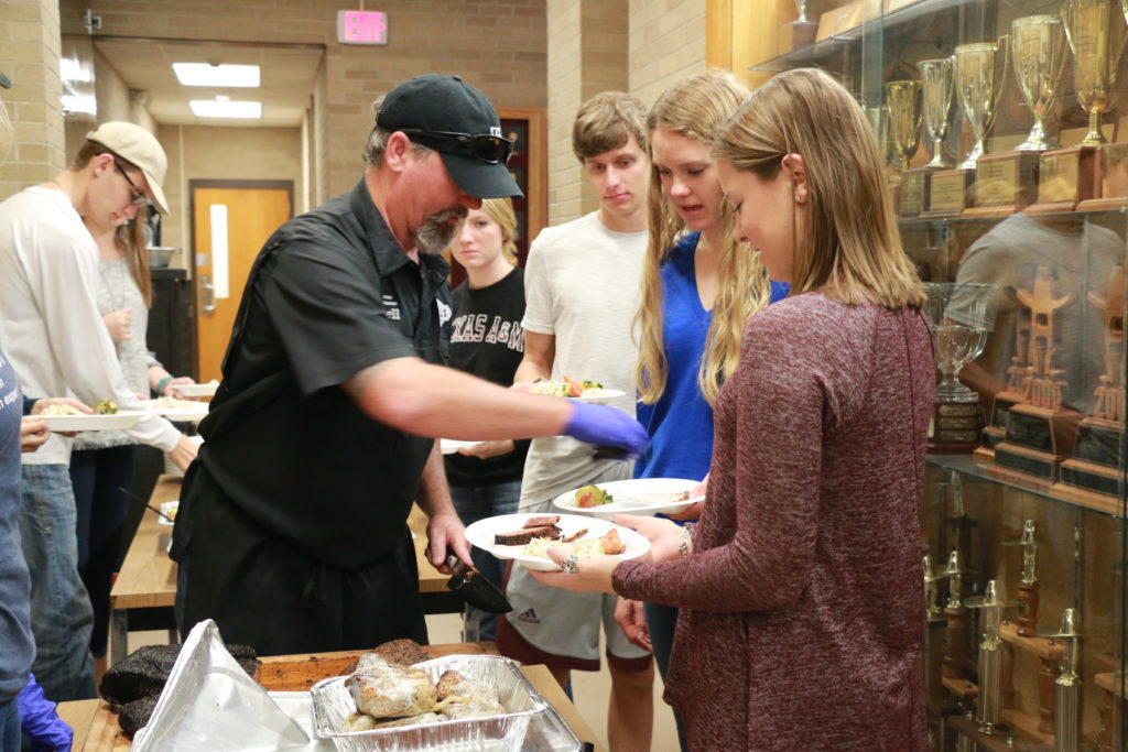 Russell Roegels serving barbecue to students