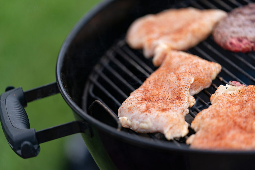 Close up pieces of meat cooking on a grill. 