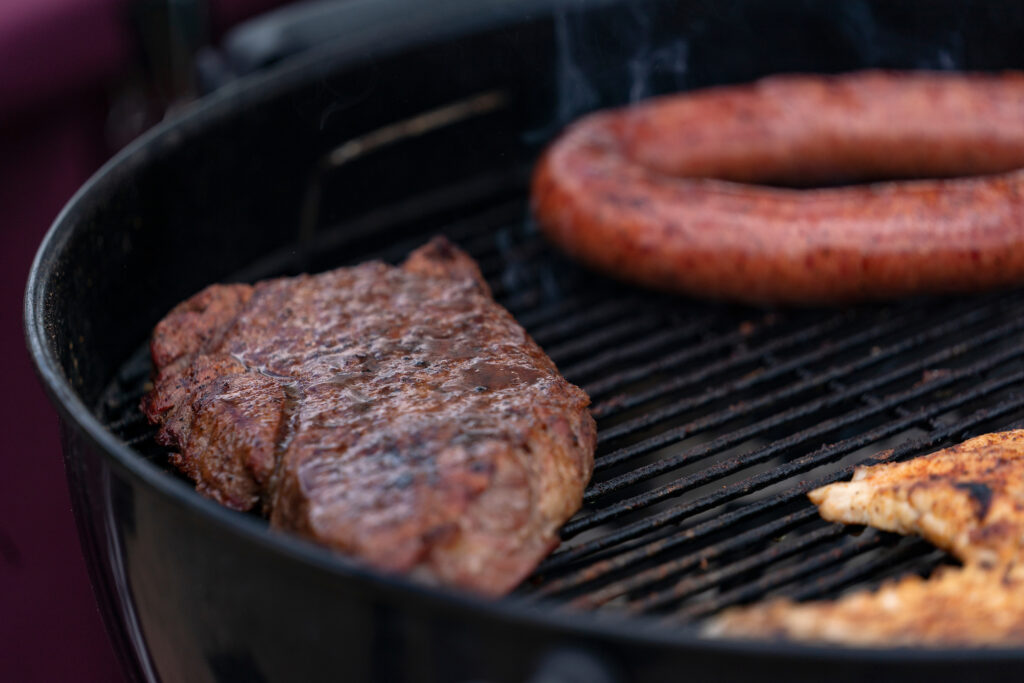 Steak and sausage on a grill.