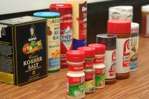 Multiple bottles of different seasonings placed on a wooden table. 