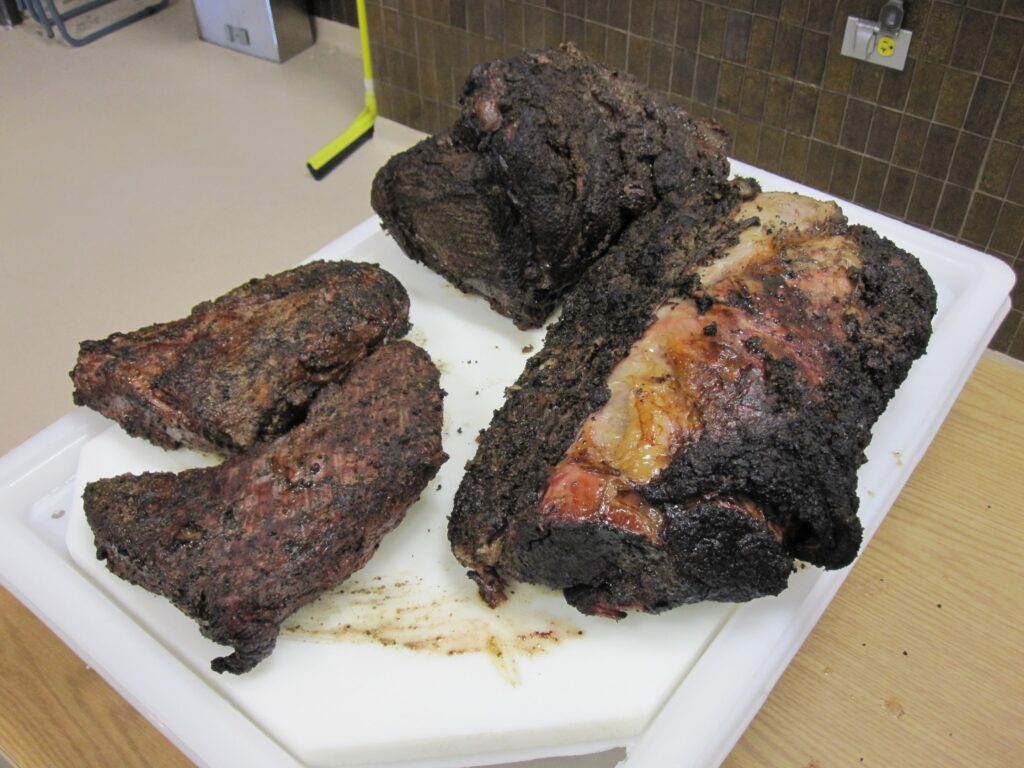 Three different pieces of brisket on a white cutting board. 