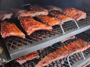 Multiple ribs on a smoker being prepared.