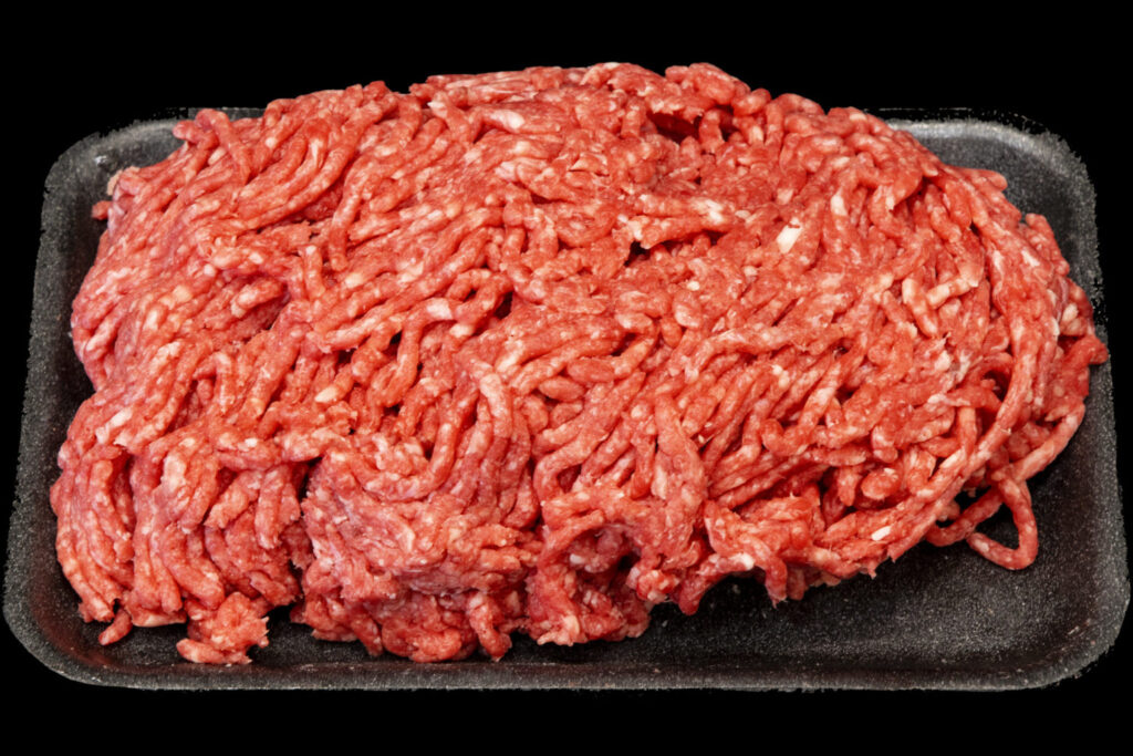 Raw ground beef on a black Styrofoam plate.