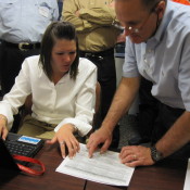 A man and a woman looking down and pointing at a piece of paper. 