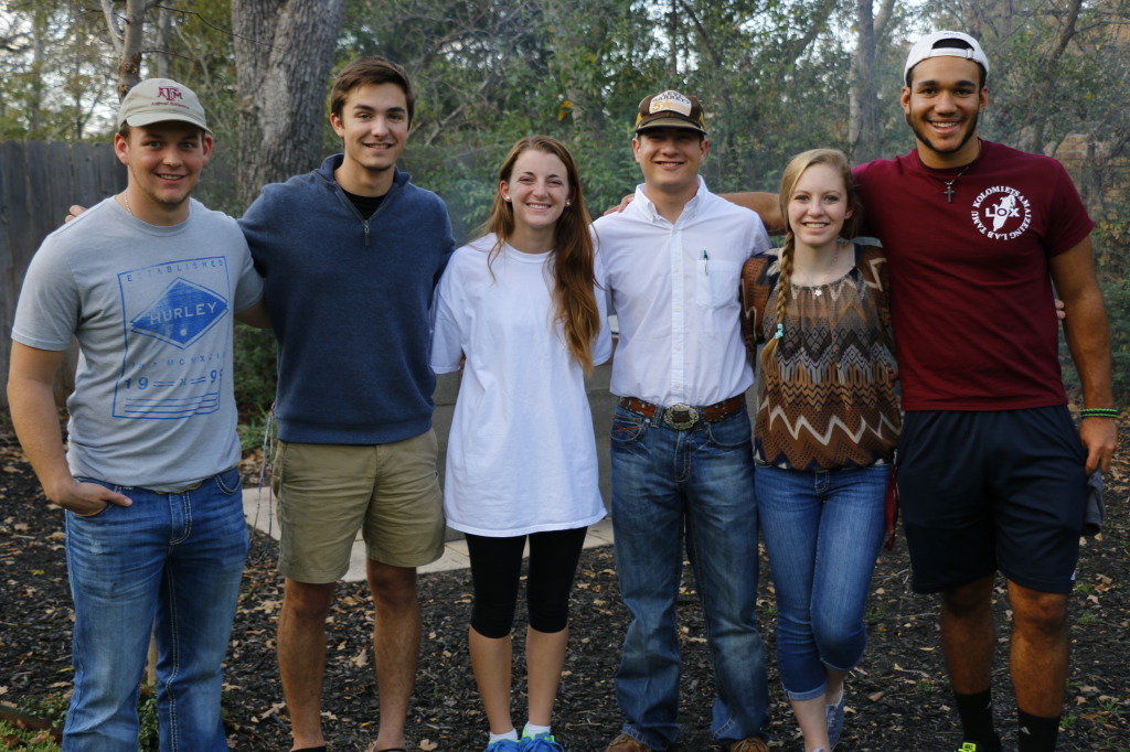 A group of students standing together smiling for a picture in an outdoor environment. 