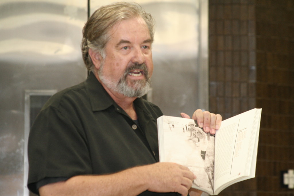 A man holding up a book and pointing towards it. 