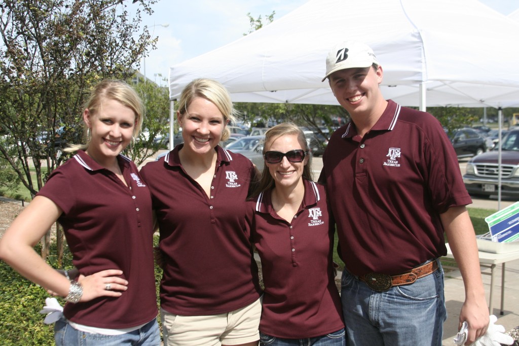 A group of four students all wearing the same maroon polo with the A&M logo. 