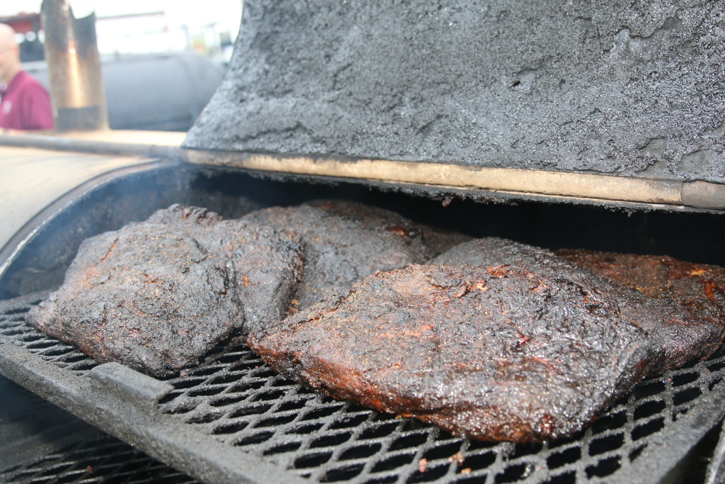 Close-up of briskets cooking on a barbecue pit.