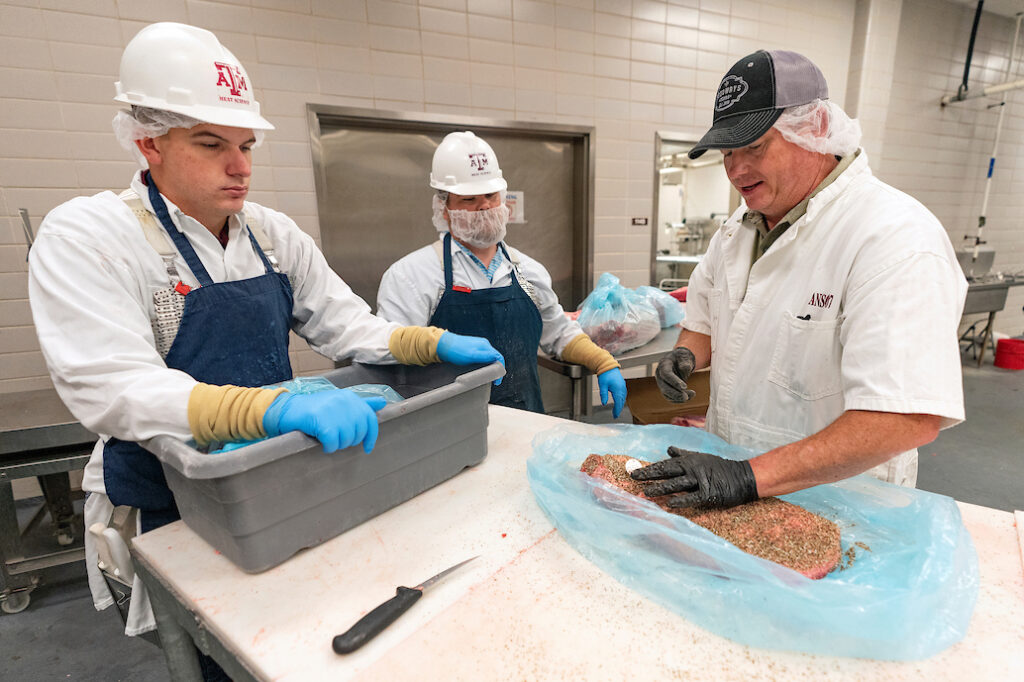 Three people preparing meat at Rosenthal Meat Science and Technology Center.