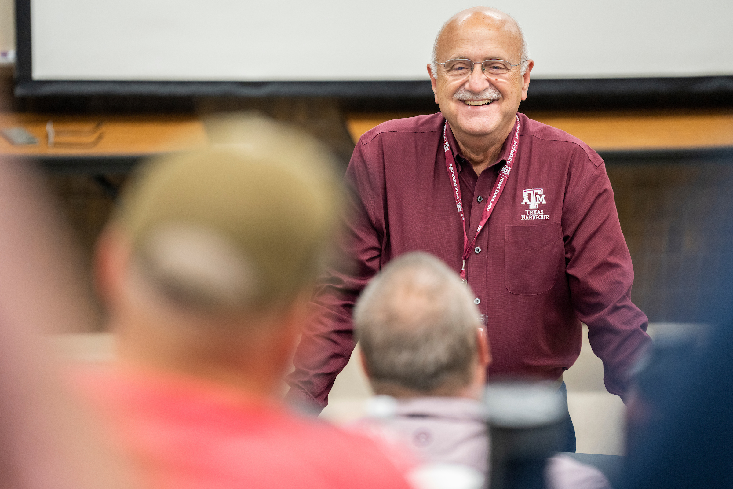 Meat science instructor at front of lecture room, smiling.