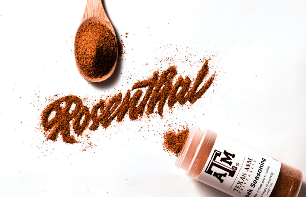 The word "Rosenthal" spelled out in barbecue seasoning on a white table, with the seasoning bottle next to it showing the Texas A&M label.